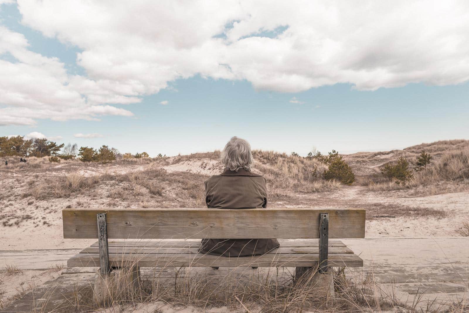 homem esperando no banco em deserto